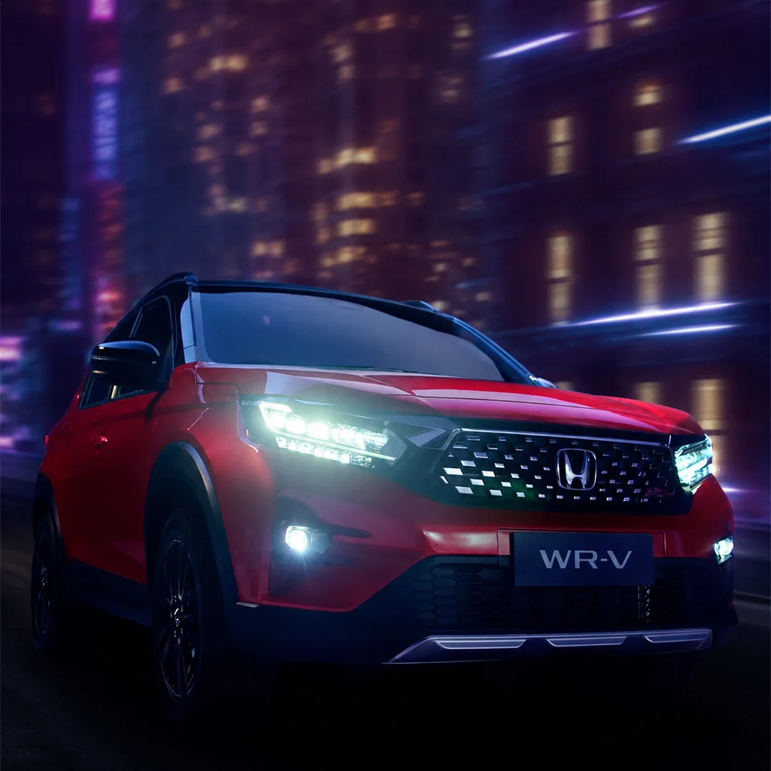 Red Honda WR-V driving through a neon-lit night scene